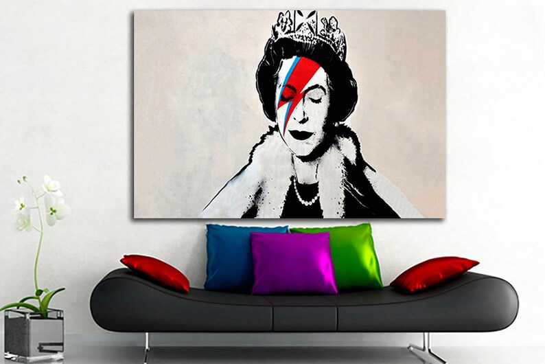 May include: A black and white portrait of Queen Elizabeth II with a red, blue, and white lightning bolt painted over her right eye. The queen is wearing a crown and a fur collar.