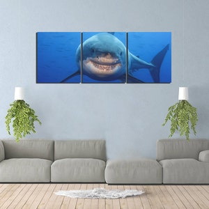 May include: A three-panel canvas print featuring a close-up of a great white shark with its mouth open, showing its teeth. The shark is swimming in blue water.