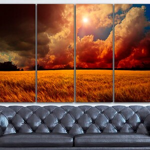 K&ouml;nnte beinhalten: Ein vierteiliger Leinwanddruck, der eine dramatische Landschaft zeigt. Das Kunstwerk zeigt ein goldenes Weizenfeld unter einem feurigen Himmel mit dunklen Gewitterwolken und einer hellen Sonne. Der Druck wird &uuml;ber einem schwarzen Ledersofa angezeigt.
