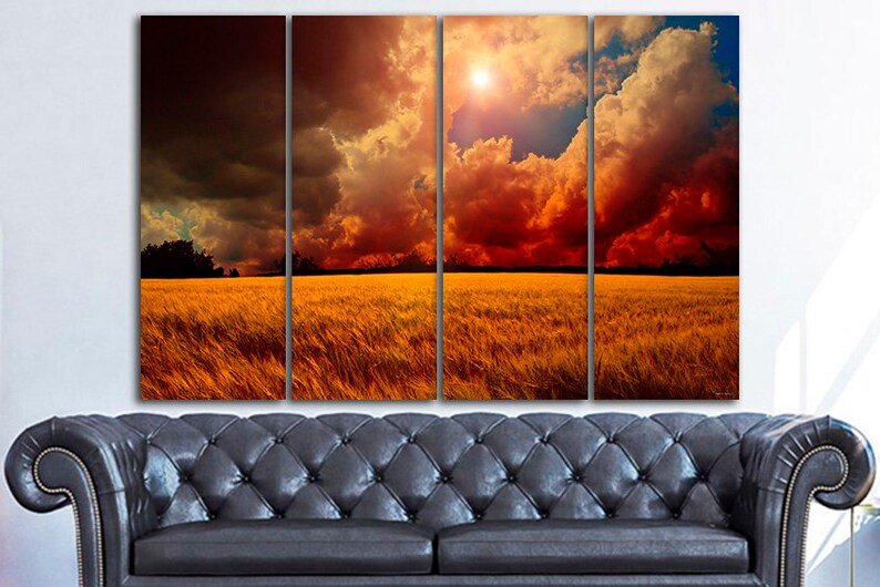 K&ouml;nnte beinhalten: Ein vierteiliger Leinwanddruck, der eine dramatische Landschaft zeigt. Das Kunstwerk zeigt ein goldenes Weizenfeld unter einem feurigen Himmel mit dunklen Gewitterwolken und einer hellen Sonne. Der Druck wird &uuml;ber einem schwarzen Ledersofa angezeigt.