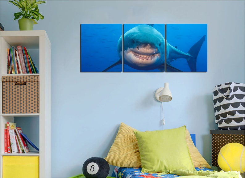 May include: A three-panel canvas print featuring a close-up of a great white shark with its mouth open, showing its teeth. The shark is swimming in blue water.