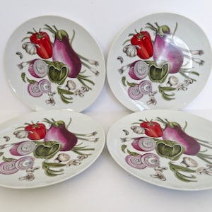 May include: Set of four white ceramic dinner plates with a colorful vegetable design. The plates feature red peppers, purple eggplants, green onions, and red onions.