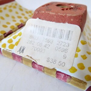 Peut inclure: Gros plan sur deux talons de chaussures d&eacute;coratifs en c&eacute;ramique. Les talons ont une base blanche avec des pois jaunes et une bordure ray&eacute;e rouge et or. Le talon est de couleur brun rouge&acirc;tre. Une &eacute;tiquette de prix est attach&eacute;e.