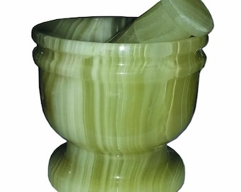 May include: Green and white marble mortar and pestle set. The mortar is a bowl shape with a wide base and a narrow top. The pestle is a smooth, rounded cylinder.