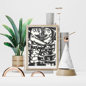 May include: A framed black and white illustration of two figures intertwined with each other. The illustration is set against a white background and surrounded by decorative objects, including a potted plant, a marble cone, and a copper rod.