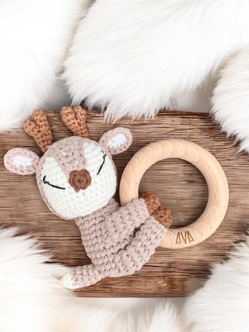 May include: A crocheted deer toy with a wooden teething ring. The ring is engraved with the name "AVA".