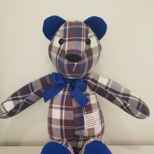 May include: A blue and brown plaid teddy bear with blue ears and feet. The bear has a blue bow and a small tag sewn on the back that reads "Matthew, This is a shirt I used to wear. Whenever you hold me Know I am there. Love, Mom."