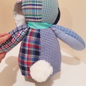May include: A patchwork bunny toy made from blue, red, and white plaid fabric. The bunny has a white fur tail and a turquoise ribbon around its neck.