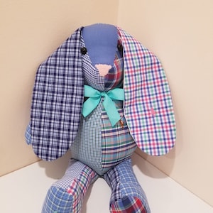 May include: A patchwork bunny toy made from blue, green, and red plaid fabric. The bunny has long ears and a blue bow around its neck.