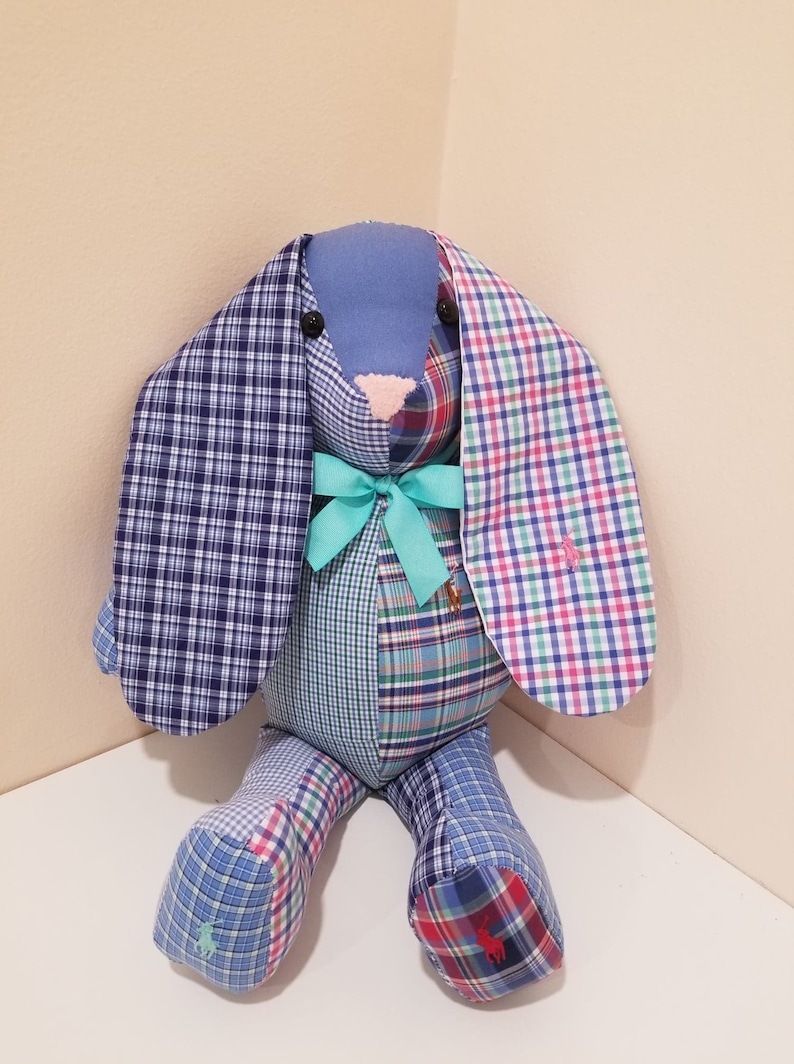 May include: A patchwork bunny toy made from blue, green, and red plaid fabric. The bunny has long ears and a blue bow around its neck.