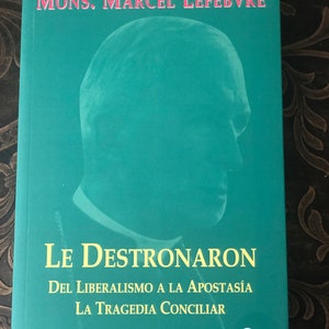 May include: A teal book cover with a portrait of a man in a clerical collar. The title is "Le Destronaron" with the subtitle "Del Liberalismo a la Apostasía La Tragedia Conciliar". The book is part of a series called "Obras Completas Tomo 1".