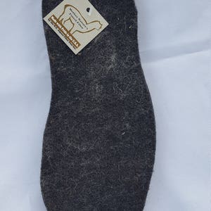 May include: A dark gray alpaca wool insole with a brown tag that reads "Mother Nature's Finest Fiber" and "Made with Pride in the U.S.A. by the N... Alpaca Fiber Pool Inc."