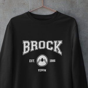 May include: Black sweatshirt with white text that reads "Brock Est. 1986 Venom" with a white spider symbol.
