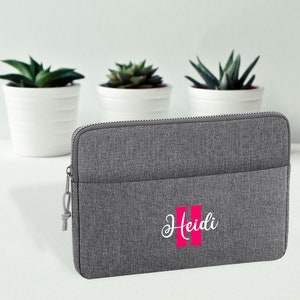 Könnte beinhalten: Graue Laptoptasche mit Reißverschluss und einem rosa gestickten Namen "Heidi".