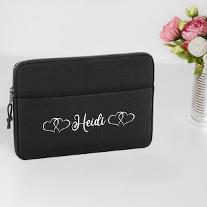 May include: Black laptop sleeve with a white embroidered design of two intertwined hearts and the name "Heidi".