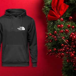 May include: Black hooded sweatshirt with a white logo that says "The North Pole" and a small image of a house.