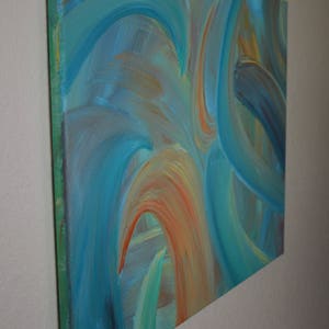 May include: Abstract painting on canvas with swirling blue, green, and orange hues. The painting has a textured surface and is framed with a green border.