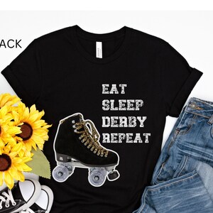 May include: Black t-shirt with a white graphic of a roller skate and the text "Eat Sleep Derby Repeat".