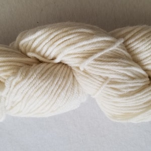 May include: A skein of off-white yarn, a soft and fluffy material for knitting or crocheting.