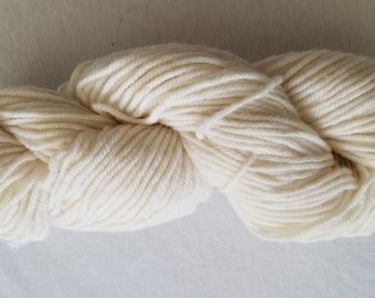 Puede incluir: Un ovillo de hilo blanco roto, un material suave y esponjoso para tejer o hacer ganchillo.
