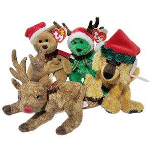 Puede incluir: Cuatro peluches de temática navideña tipo beanie babies: un reno marrón, un reno verde, un oso marrón y un perro amarillo. Cada beanie baby lleva un gorro de Papá Noel rojo.