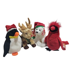 Könnte beinhalten: Vier Plüschtiere, die in festliche Kleidung gekleidet sind. Ein Pinguin mit einer roten Weihnachtsmütze, ein Rentier mit einem rot-grünen Schal, ein Eisbär mit einer roten Weihnachtsmütze und ein Kardinal mit einer roten Weihnachtsmütze.