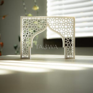 May include: White decorative archway with a geometric pattern and the word "TAQWA" inscribed in the center.