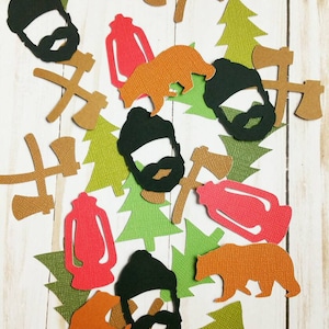 May include: A collection of paper cutouts in various shapes and colors, including bears, trees, axes, and lanterns. The cutouts are made of textured paper and have a rustic, woodland theme.