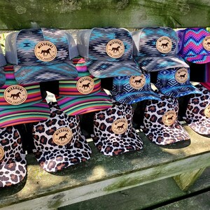 May include: A collection of 14 trucker hats with a variety of colorful patterns and designs. The hats feature a brown leather patch with the text "Missouri" and a horse silhouette. The hats are arranged in a row on a wooden bench.