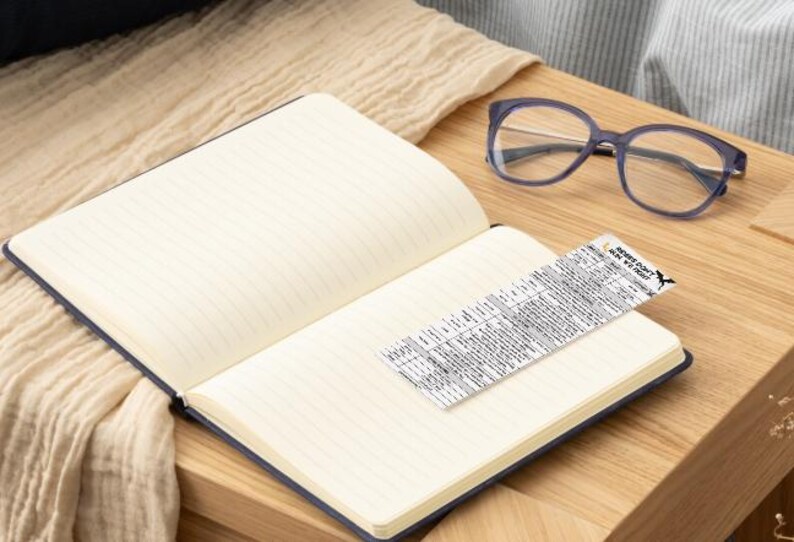 May include: A blue notebook with lined pages is open on a wooden table. A pair of eyeglasses and a small piece of paper with text are on the table. The paper has the text "Secret Code: How We Do This".