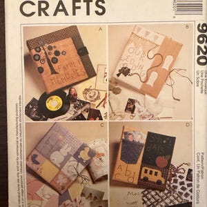May include: McCall's Crafts pattern envelope 9620 featuring four fabric-covered photo album designs. Design A shows a tree with buttons, B features 'Our Wedding' text, C displays a patchwork quilt style, and D includes a denim pocket and 'School Days' text.