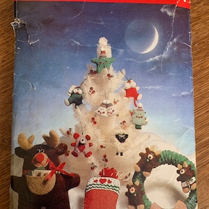 May include: A vintage craft pattern from Butterick, featuring a white Christmas tree with various ornaments, including a reindeer, a stocking, a wreath, and a snowman. The pattern number is 6053.