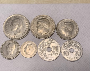 May include: A collection of silver Greek coins, featuring portraits and inscriptions. The coins vary in size and include denominations like 20 and 10 Lepta. Some coins are dated 1959, 1970, and 1964.