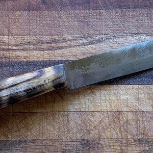 May include: A handmade knife with a dark wood handle and a metal blade. The blade has a slight curve and a sharp point. The handle has two brass rivets.