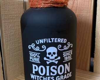 May include: Black glass bottle with a cork stopper, wrapped with orange twine and gold thread. The bottle has white text that reads "UNFILTERED 100% PURE POISON WITCHES GRADE Use with Caution" with a skull and crossbones graphic.