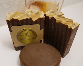 May include: Three bars of brown goat milk soap with a label that reads "Grubby Goat Soap Co. Smithville, sd. THE GAMBLER BATH BAR olive oil, goat milk, lard, organic coconut oil,  lavender essential oil, bourbon whiskey fragrance oil 3.5 oz. net wt."