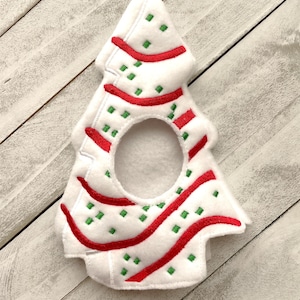 May include: White felt Christmas tree ornament with red and green embroidered stripes and a hole in the center.