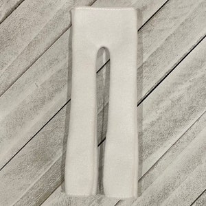 May include: White felt pants for a doll or elf. The pants are made of soft, white felt and have a simple design.