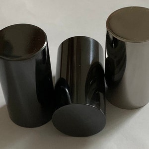 May include: Three cylindrical metal bottle stoppers in different finishes: black, dark gray, and silver.