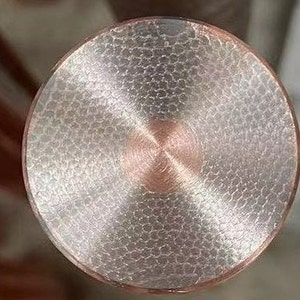 May include: Close-up of a round, silver-colored metal object with a textured surface. The center of the object has a smooth, circular area with a brushed finish.