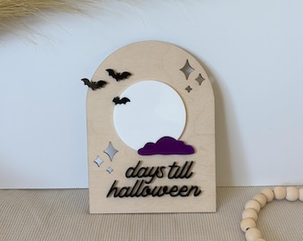 May include: Wooden Halloween countdown sign with a light wood finish. Features a white moon, purple cloud, and black bats. The sign reads "days till halloween" in black script. Decorative stars are also included.