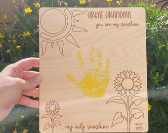 May include: Wooden plaque with engraved sun and sunflower designs. The plaque includes the text "GREAT GRANDMA you are my sunshine..." and "...my only sunshine" with a yellow handprint and the name "Noah 2025".