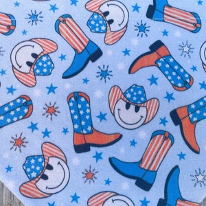 Może przedstawiać: Niebieska bandana z powtarzającym się wzorem czerwono-biało-niebieskich kowbojskich kapeluszy z uśmiechniętymi buźkami i kowbojskich but&oacute;w. Kapelusze i buty mają wz&oacute;r w gwiazdki i paski.