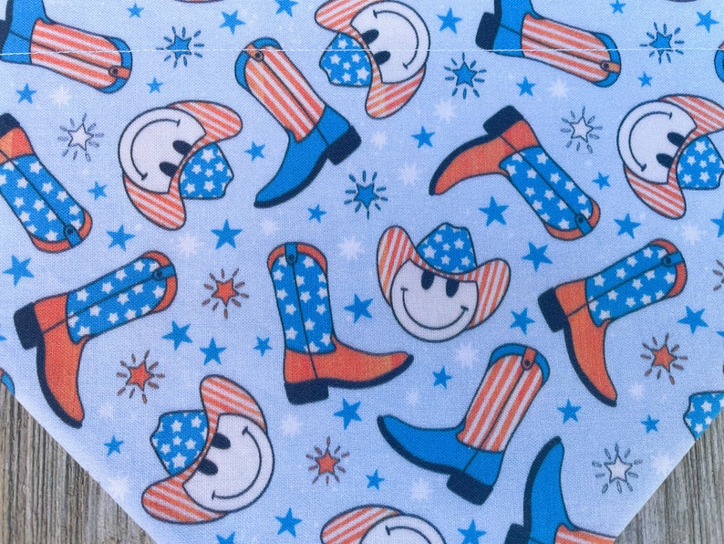 Może przedstawiać: Niebieska bandana z powtarzającym się wzorem czerwono-biało-niebieskich kowbojskich kapeluszy z uśmiechniętymi buźkami i kowbojskich but&oacute;w. Kapelusze i buty mają wz&oacute;r w gwiazdki i paski.