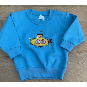 May include: A light blue sweatshirt with a yellow submarine embroidered on the front. The submarine has two rabbits inside and the text "1015" on the side.