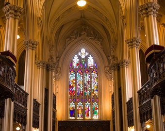 May include: A stained glass window with colorful designs in a church with high vaulted ceilings and ornate wooden balconies.