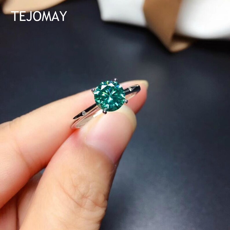Handcrafted green moissanite ring featuring a round cut center stone and polished silver band