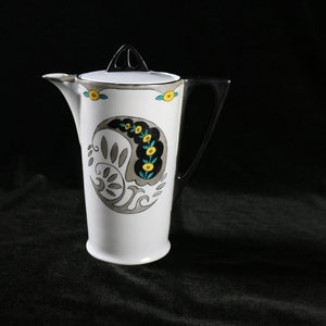 May include: White ceramic teapot with a silver lid and handle. The teapot has a black and gray paisley design with yellow flowers.