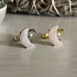 Può includere: Due anelli a forma di luna crescente con una pietra rosa incastonata in una fascia d'argento e oro.