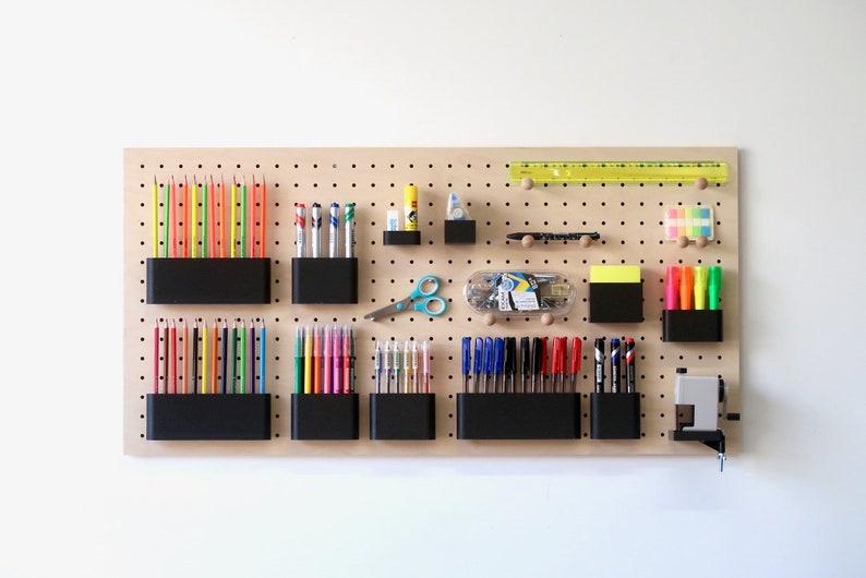 A wooden pegboard with baskets, cups, and hooks filled with art supplies.